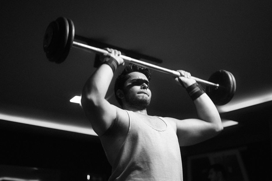An athlete lifting a barbell in high-contrast black and white.