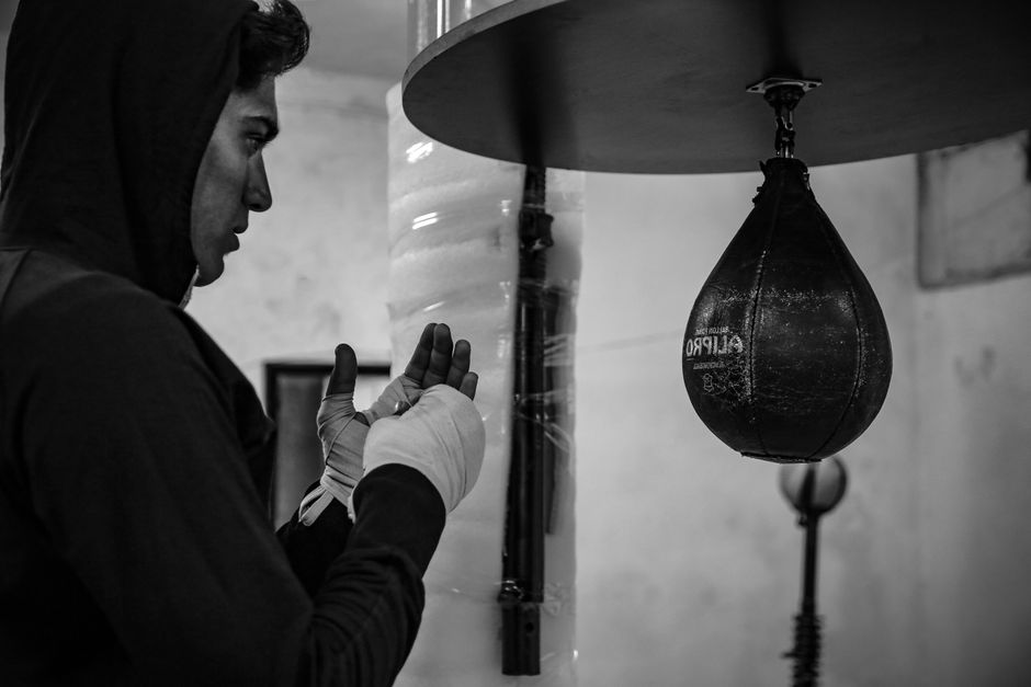 A boxer training on a heavy bag, captured in dramatic black and white.
