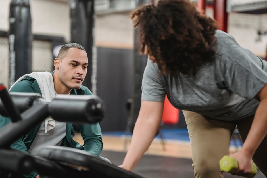 A coach guiding a client through a strength exercise.